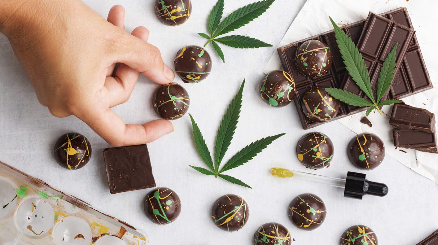 CBD chocolate pieces with cool splattered cocoa butter designs on white background above view. THC Edibles chocolates.